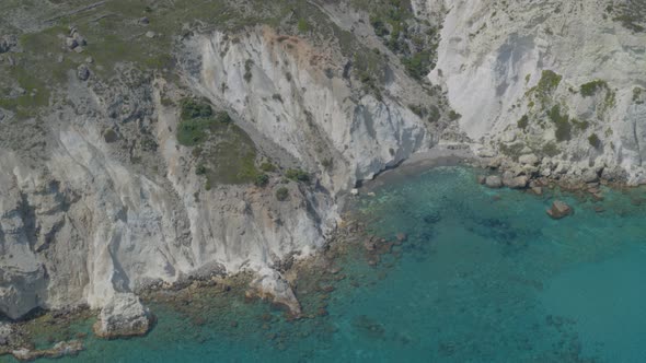 Aerial Pan of Cliffs Cascading into the Beautiful Blue Aegean Sea in Milos alt