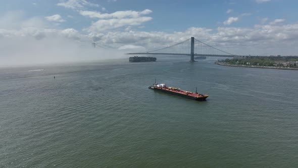 An aerial view of Gravesend Bay in Brooklyn, NY on a cloudy day with blue skies. A dense fog is over alt
