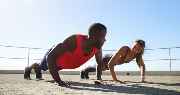 Couple doing push-up exercise on a promenade at beach 