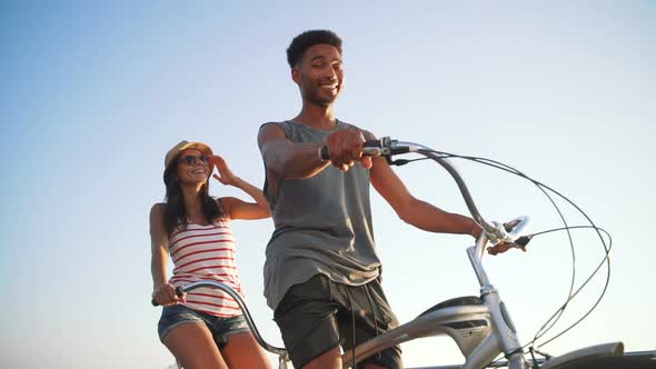 Portrait of a Mixed Race Couple on Tandem Bicycle Outdoors Near the Sea Slow Motion alt