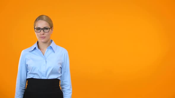 Beautiful Young Woman in Eyeglasses Showing Thumbs Up on Orange Background alt