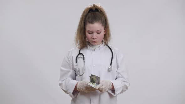 Little Doctor Counting Bribe Money Hiding Cash in Pocket Looking at Camera alt