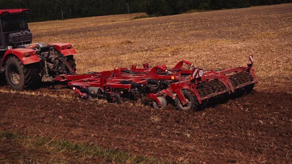Tractor on land cultivating. Tractor with disk harrow system plowing ground on cultivated farm alt