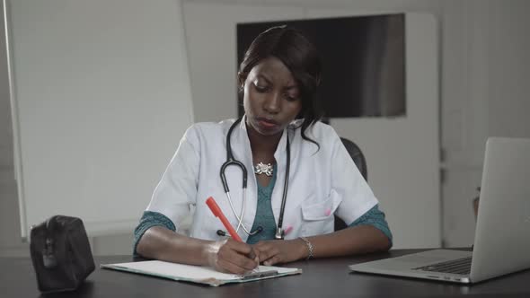 Medicine, People and Healthcare Concept - Happy Female African American Doctor or Nurse Writing alt