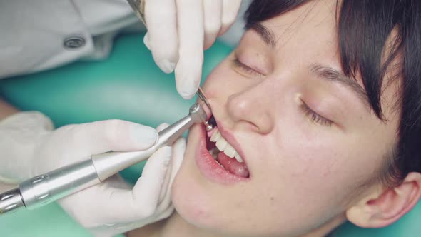 Young woman receives professional teeth cleaning in cosmetic dentistry clinic alt