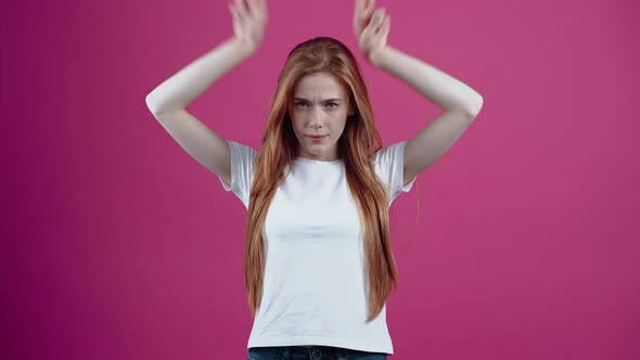 The Irritated Young Woman Puts Her Hands to Her Head in the Form of Horns and Looks Frustrated Ahead alt