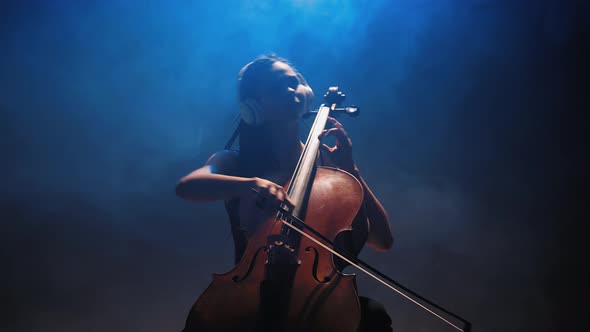 Young Beautiful Woman Playing a Melody on Cello. Smoky Dark Studio