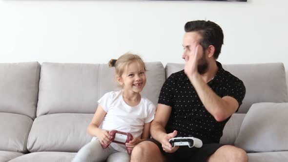 Cheerful Caucasian Father Playing Videogames Emotionally Together with His Cute Daughter Winning