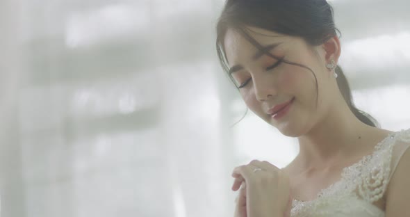 Slow Motion Smiling Beautiful Asian Bride In Wedding Dress Praying To The God. alt