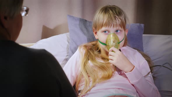 Grandmother Sits at the Bedside of a Cold Baby Who Does Inhalation alt
