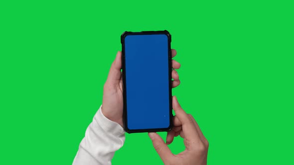 Woman hand holding smartphone with blue screen on chroma key green screen background.