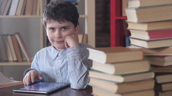 happy schoolboy at his Desk looks at the camera and laughs. alt