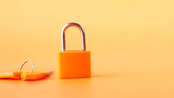 Orange Color Padlock And Key on Table alt