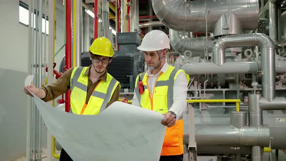 Engineer and Foreman are discussing the plant layout on the blueprint in the factory boiler room