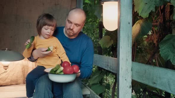 Father and Small Child Eat Fresh Organic Vegetables From Farm Sitting on Porch