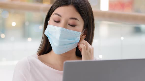 Close Up Asian Girl with Laptop Feels Tired of Pandemic Safety Rules Takes Off Medical Mask Inhales alt