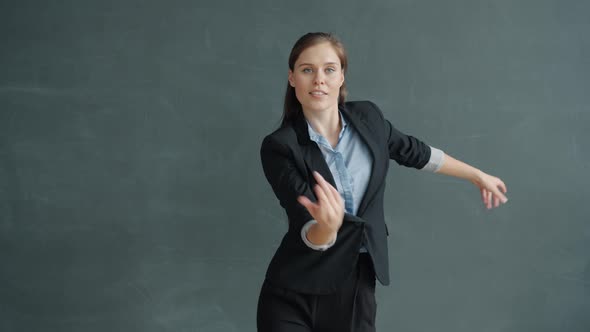 Slow Motion Portrait of Gorgeous Young Lady in Elegant Suit Dancing on Dark Background alt