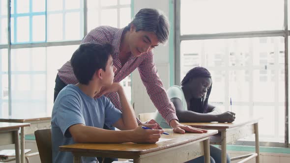 Male Teacher Checking Multi Ethnic Classroom Test alt