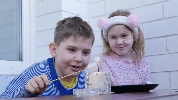 Two Interesting Teenagers a Boy and a Girl Fry Marshmallows on Sticks From a Burning Candle Sitting alt