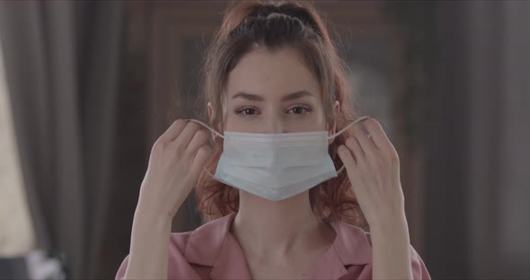 Joyful Woman Takes Off Surgical Mask On Her Face And Looks Directly At The Camera