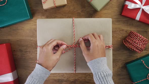 Woman hands tying bow with string on top of  Christmas gift box