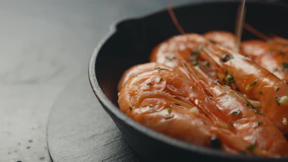 A small frying pan with shrimps in oil with spices