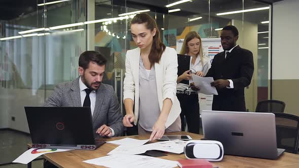 Businessman Signing the Documents in Boardroom while His Business Partners Discussing the Project alt