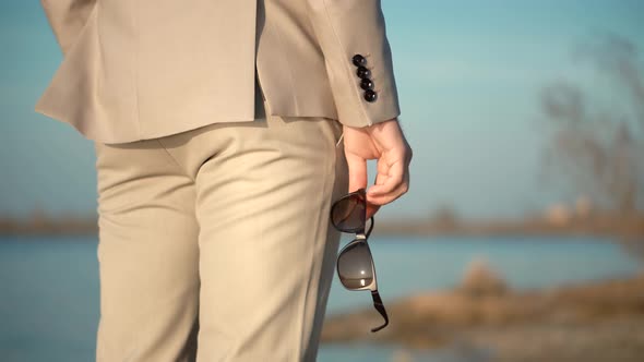 Man With Sunglasses In Hand.Businessman Hand Holding Pair Of Polarized Sunglasses. alt