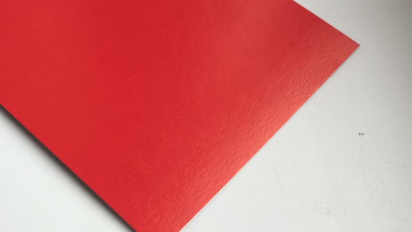 4k video, close-up, one sheet of red paper rotating on a white background, top view.