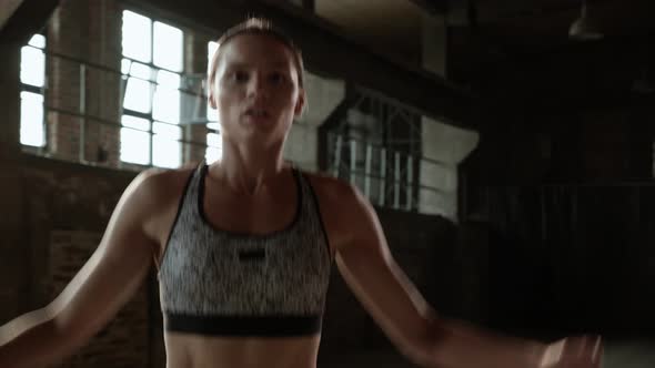 Fit woman doing jumping jack exercise at fitness gym alt