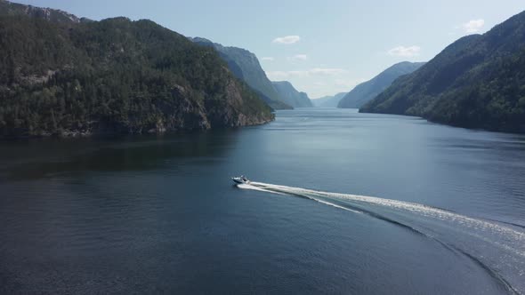 Shot from above, speed boat cruising in Norwegian fjord, idyllic landscape alt