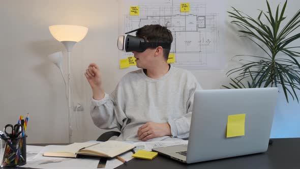 Male Architect in Virtual Reality Helmet Uses Gestures To Manage a Project