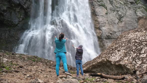 Woman with Her Daughter Standing Near Waterfall alt