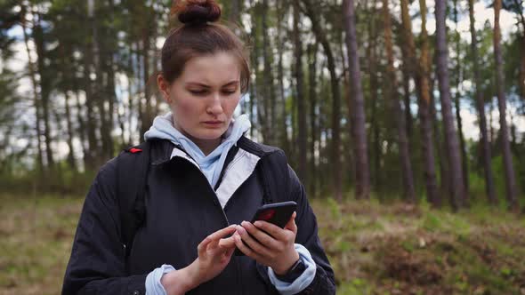 Woman with a Backpack Looking the Route on the Maps on the Phone in the Forest