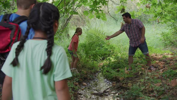 Kids at summer camp cross small creek on nature walk