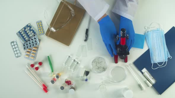 Doctor Wearing Medical Protective Gloves Working in Modern Laboratory Using Microscope Top View alt