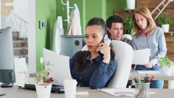 Young Businesswoman Having a Phone Conversation and Reading Some Documents alt
