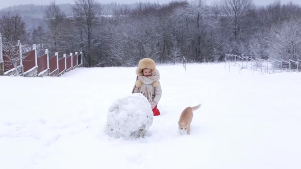European Girl and Her Cat are Playing Outside in Snowy Weather