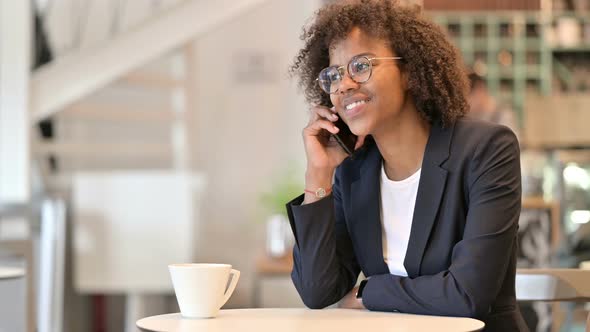 Cheerful African Businesswoman Talking on Smartphone at Cafe  alt
