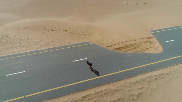 Aerial view of woman doing exercise in road cover by sand on Abu Dhabi, U.A.E alt