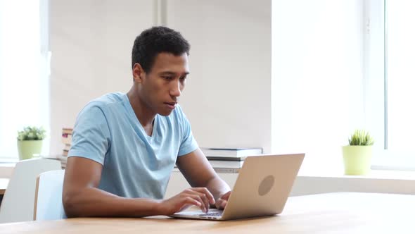 Serious Black Man Looking Toward Camera, Working on Laptop alt