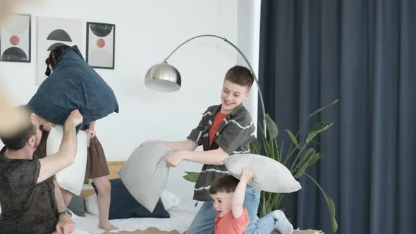 Dad and Three Happy Children are Fighting Pillows on the Weekend alt