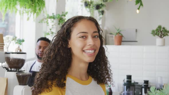 Portrait of happy biracial woman looking at camera and smiling at cafe alt