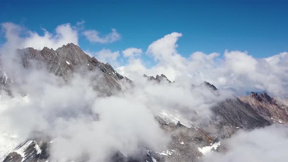 Aerial travelling of sharp edged montain range in the swiss alps with clouds in summer alt
