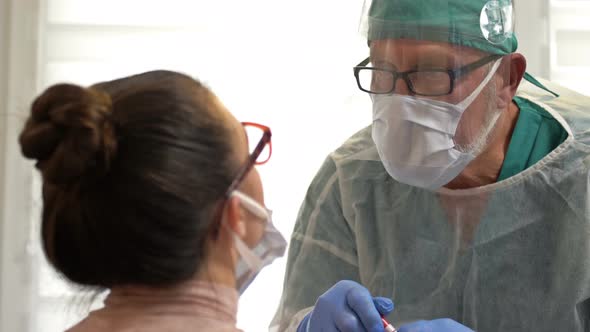 Female Patient Getting Tested with a Buccal Swab for Coronavirus By a Medical Worker Dressed  alt
