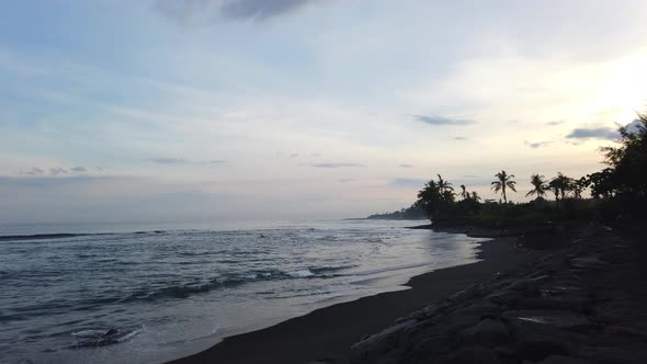 Time lapse of sunset on black sand beach Pantai Saba Gianyar Bali Indonesia clouds blue sky palms