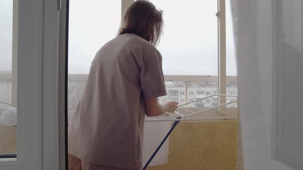 Woman Dries Clothes on the Balcony