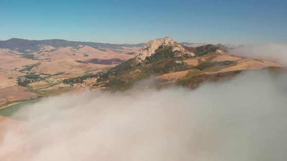 Drone flies though clouds to reveal mountain peak in the distance