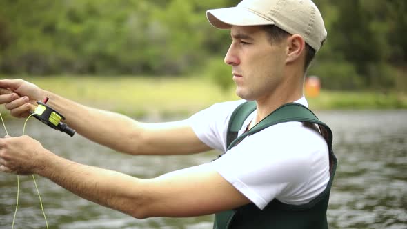 Slow Motion Shot of a Caucasian man casting his hook while Fly Fishing. He is standing in the middle alt