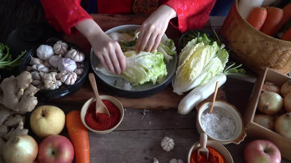 Asian women wearing Korean traditional costumes (hanbok) are Sprinkling salt by hand and Kimchi alt